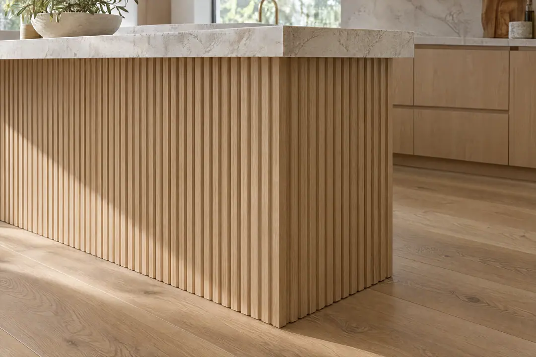 Fluted white oak island end panel beneath a thick quartzite countertop