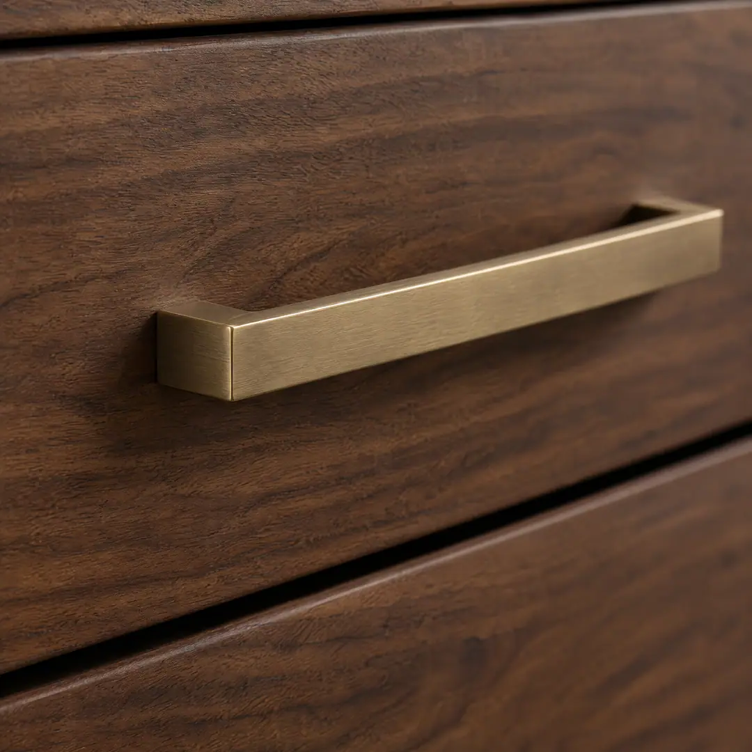 Close-up of a brushed bronze bar pull on a walnut drawer front